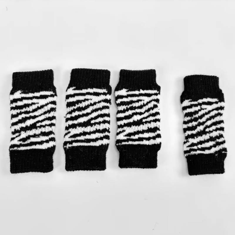 Vier schwarz-weiß gestreifte Strickhandgelenkwärmer oder fingerlose Manschetten in einer Reihe auf weißem Hintergrund angeordnet.