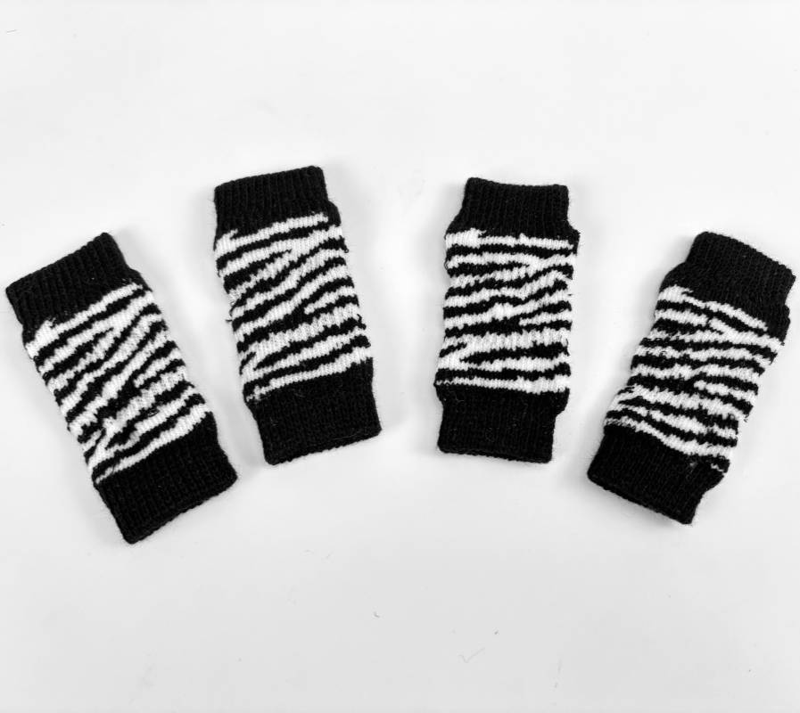Vier schwarz-weiß gestreifte Strickarmbänder auf weißem Hintergrund ausgelegt.