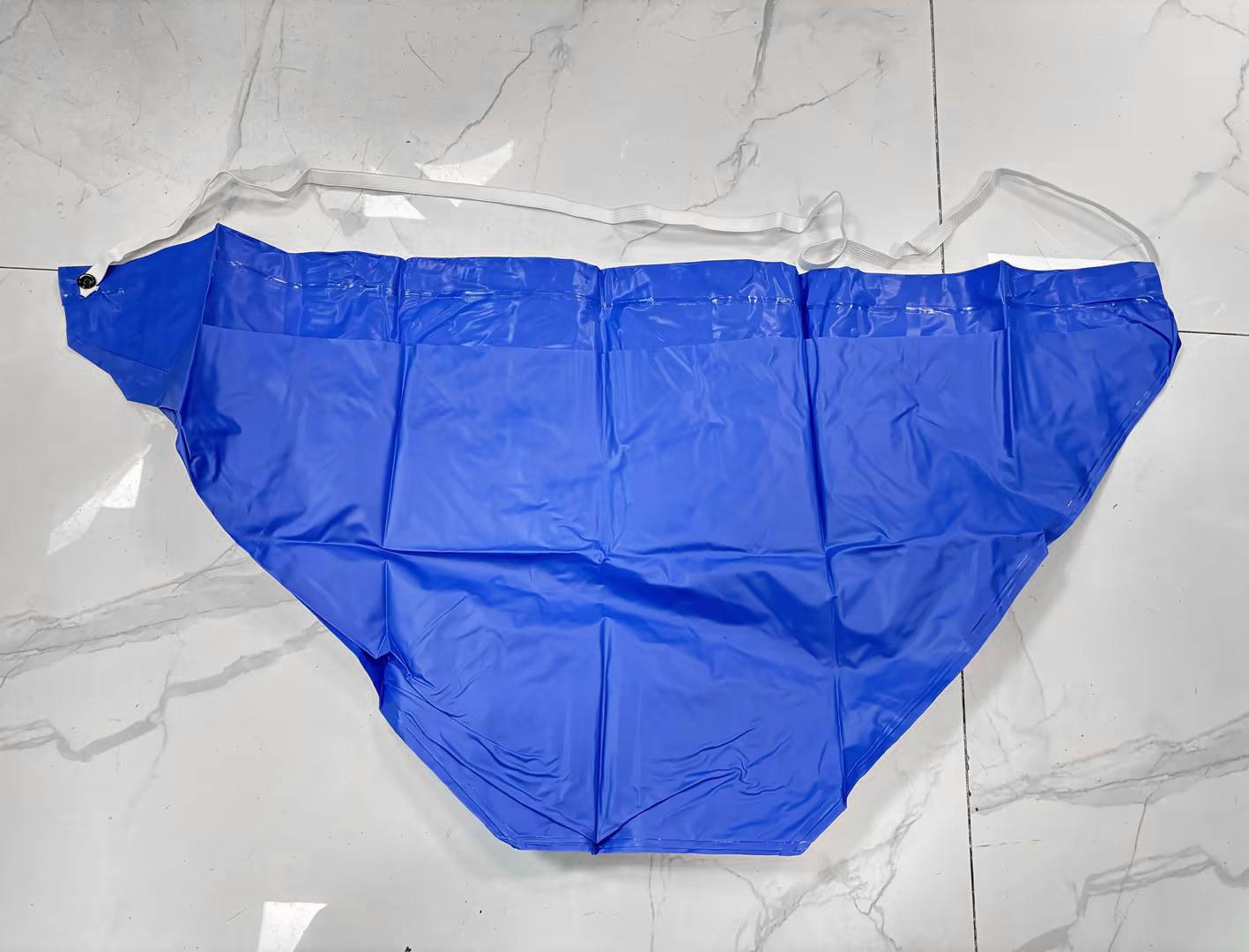 Blaue Einweg-Unterwäsche flach auf einem Marmorboden ausgelegt, mit breitem elastischem Bund und Seitenbändern.