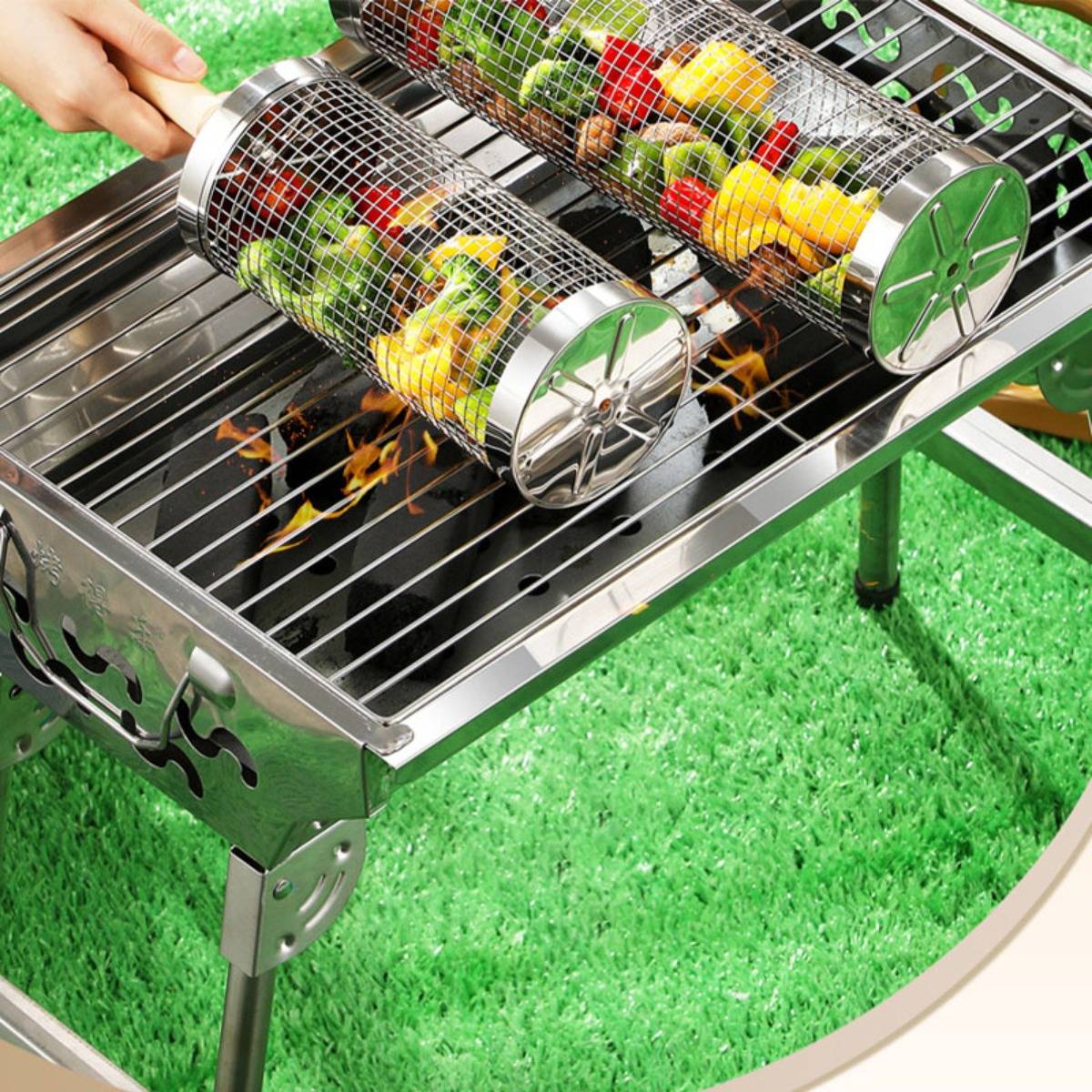 Eine Hand dreht zwei Edelstahl-Grillkörbe über einem offenen Holzkohlegrill um, in denen gemischtes Gemüse ggart.