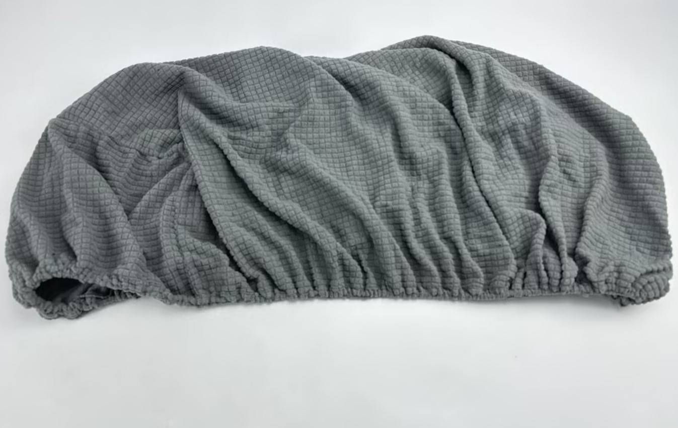Graue elastische Duschhaube mit strukturiertem Stoff und gerafften Kanten auf weißem Hintergrund.