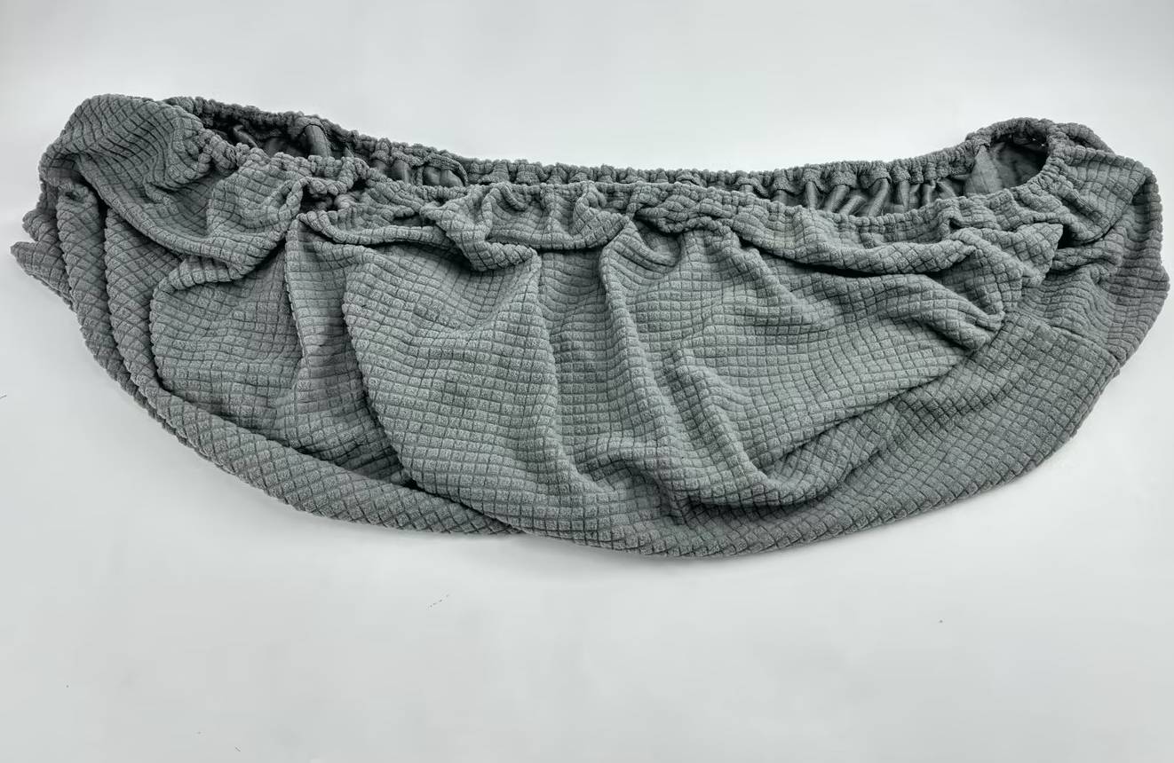 Graue gesteppte Bauchtasche mit geraffter Rüschenkante und Reißverschlusstasche, gezeigt vor weißem Hintergrund.
