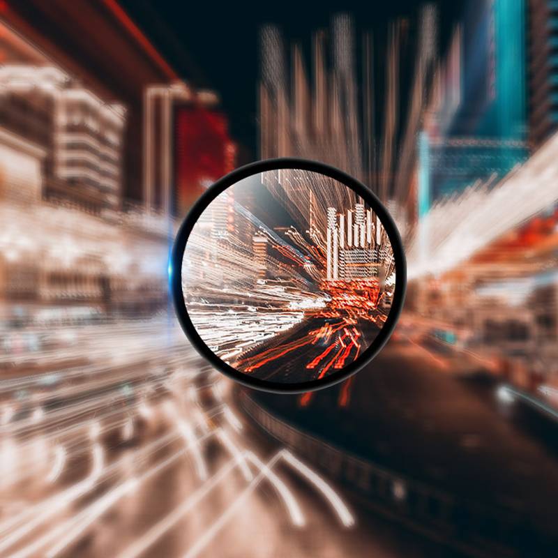 Lupe vergrößert eine unscharfe Stadtszene mit Lichtschweifen, die Bewegung, Geschwindigkeit und urbane Datenanalyse suggerieren.