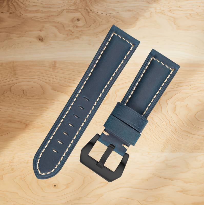 Zwei marineblaue Lederuhrenarmbänder mit creme Naht und schwarzer Schnalle auf einer hellen Holzoberfläche.