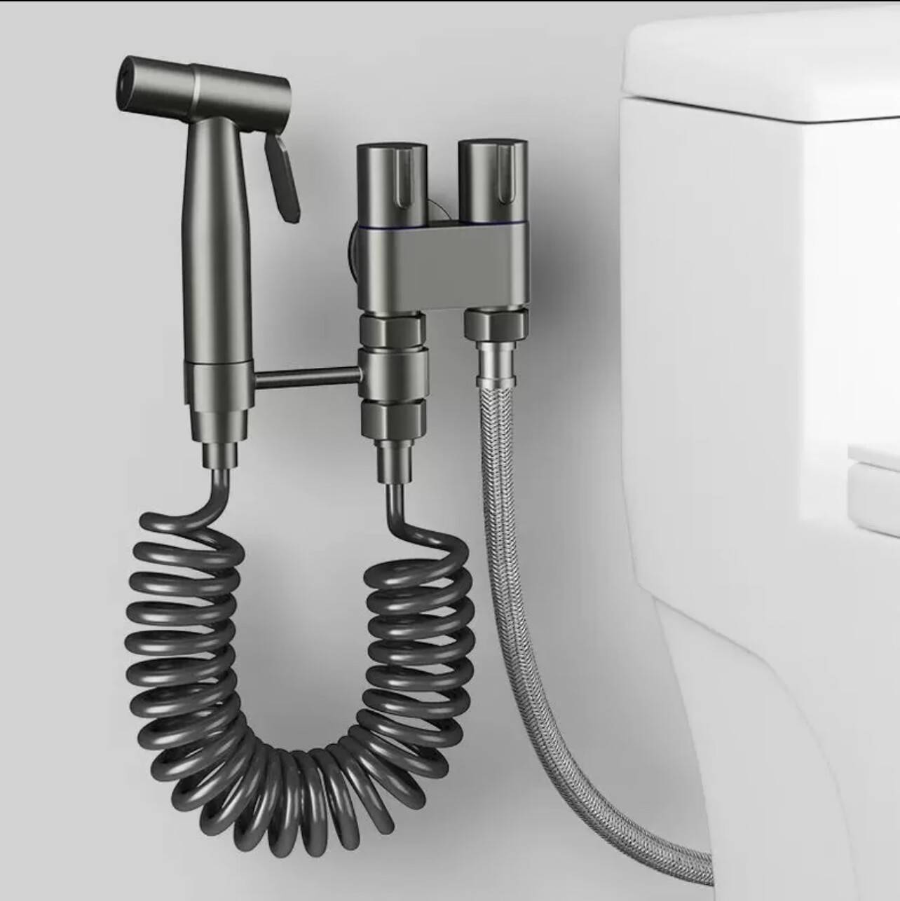Schwarzer Bidet-Sprüher neben einer Toilette angebracht, mit einem aufgerollten Schlauch und Metallverbindungsstück