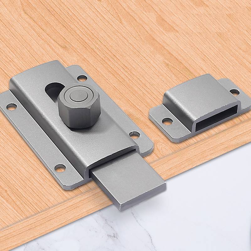 Nahaufnahme eines grauen Metall-Schieberiegels, der auf einem Holzbrett montiert ist, mit ausgefahrenem Riegel und einer passenden Halterplatte daneben.