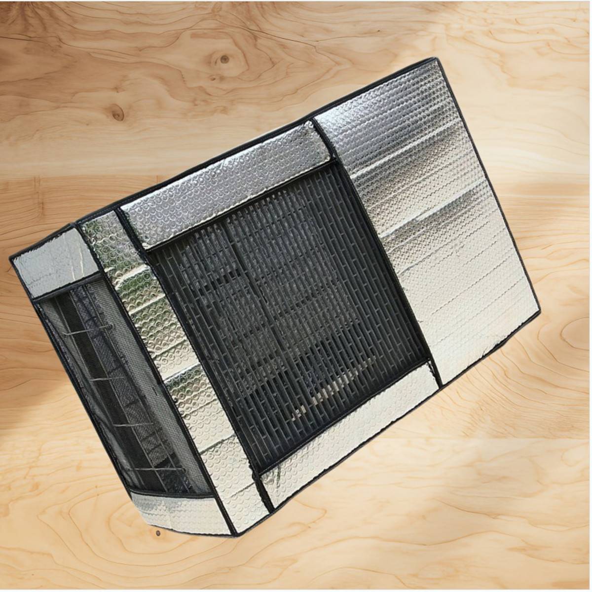 Eine rechteckige isolierte Box mit einem schwarzen vorderen Gitter und silbernen reflektierenden Paneelen, gezeigt auf einer Holzoberfläche.