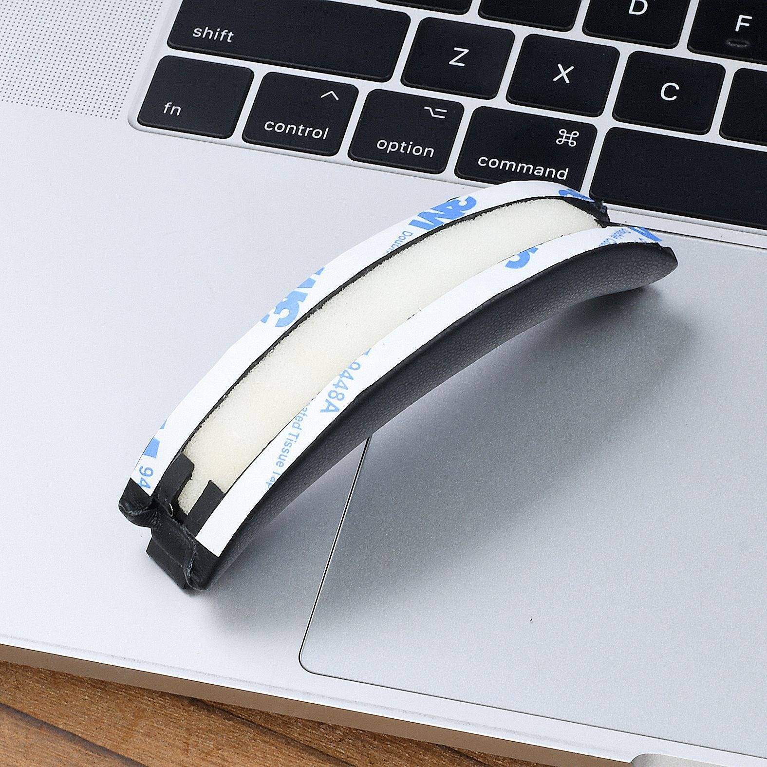Ein gekrümmter Schaumstoff-Klebestreifen ist auf der Handballenauflagefläche eines Laptops in der Nähe des Trackpads und der Tastatur angebracht, vermutlich ein Polster- oder Griffzubehör.