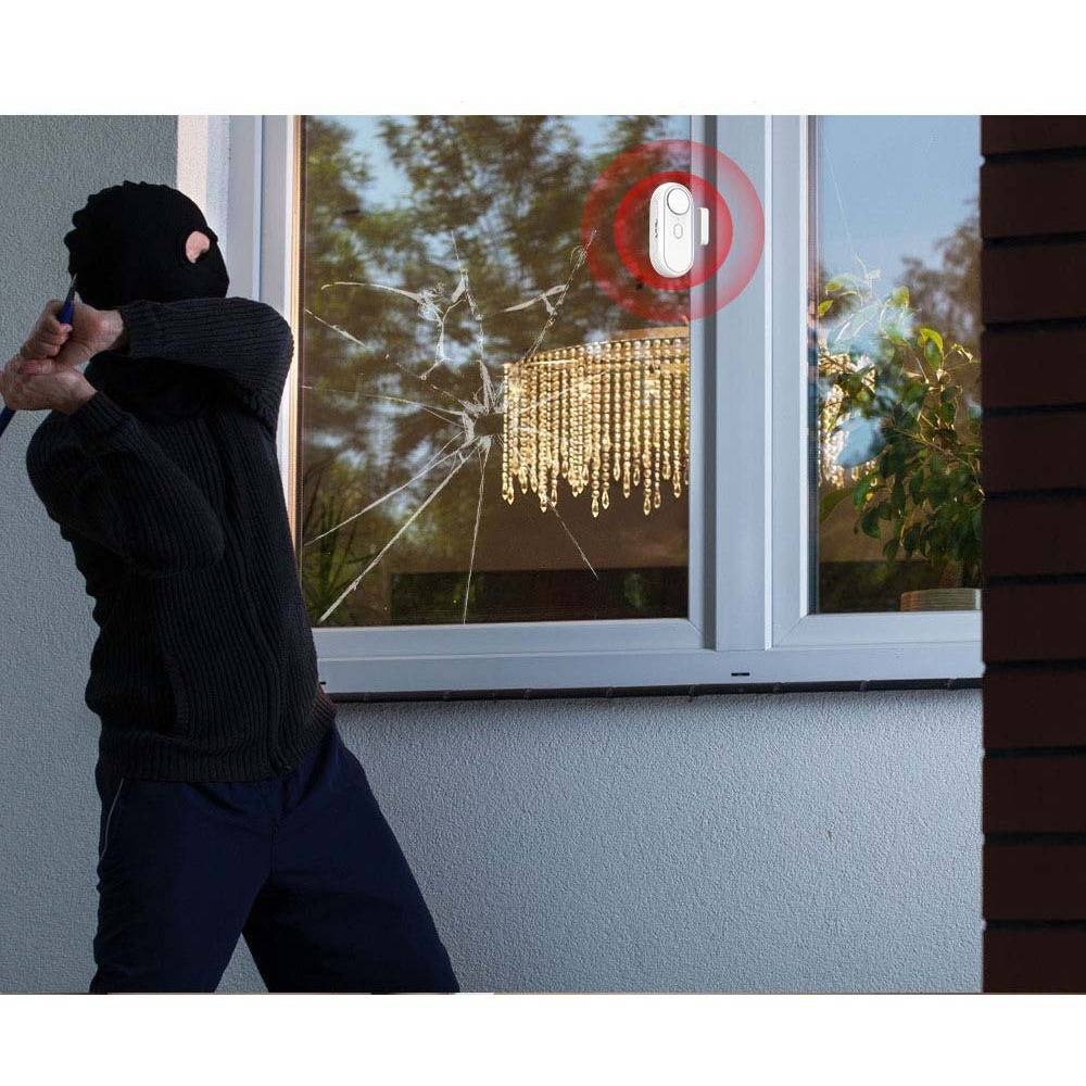 Vermummter Einbrecher, der mit einem Baseballschläger eine Scheibe zerschlägt, während auf dem Rahmen ein hervorgehobenes Sensor- oder Alarmgerät zu sehen ist.