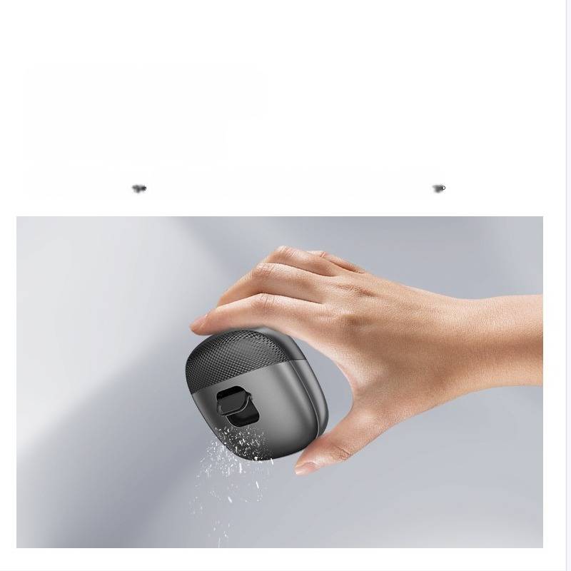 Hand, die ein kleines schwarzes elektronisches Gerät hält, mit Wasser, das von unten gegen einen grauen Hintergrund spritzt.
