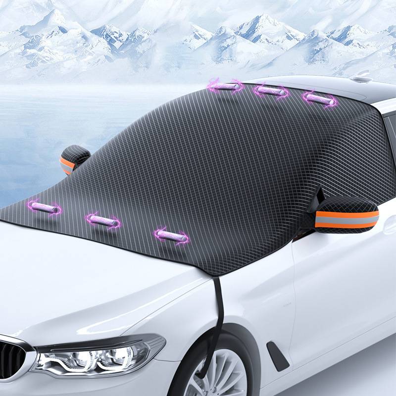 Weißes Auto mit einer großen schwarzen Windschutzscheiben-Abdeckung angebracht, vor verschneitem Bergeshintergrund.