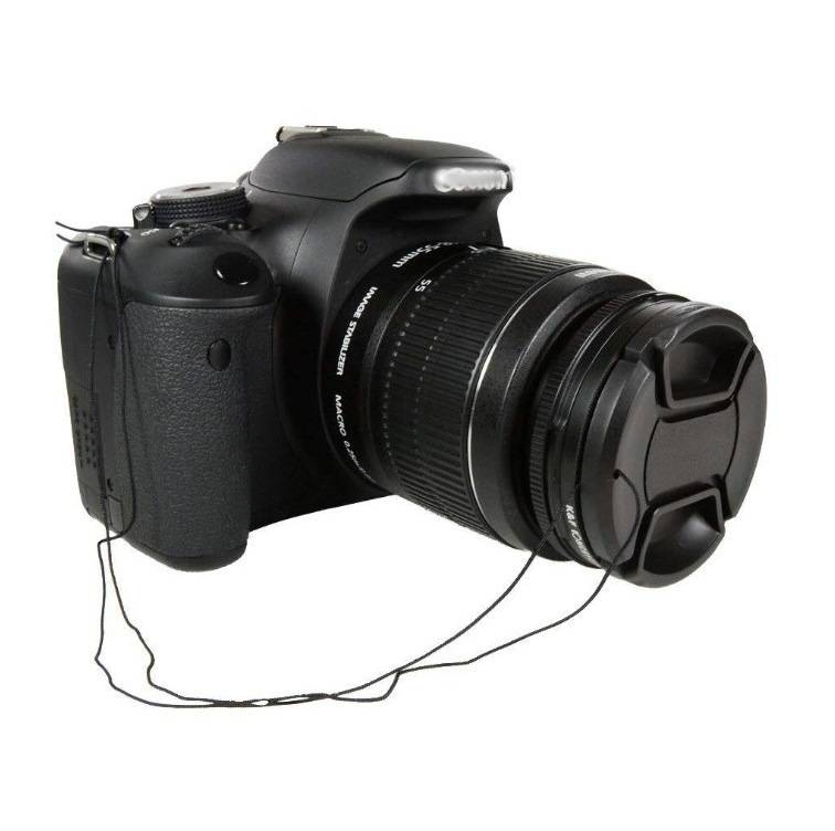 Schwarze DSLR-Kamera mit Objektivdeckel und Riemen auf weißem Hintergrund.