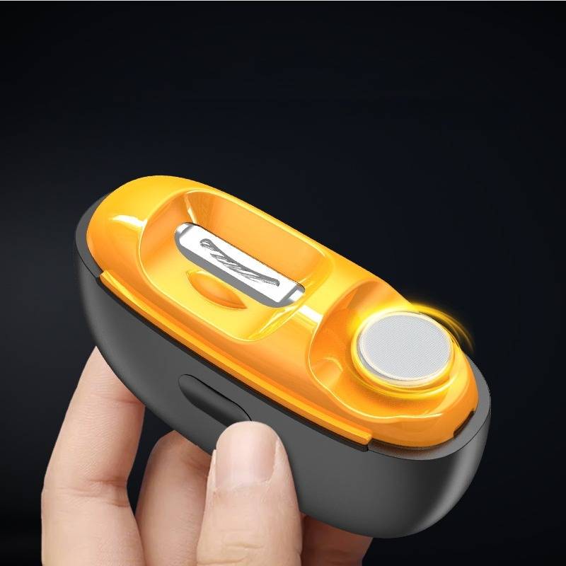Eine Hand hält einen kleinen schwarz-orangefarbenen elektrischen Nagelschneider mit einem runden weißen Knopf vor einem dunklen Hintergrund.