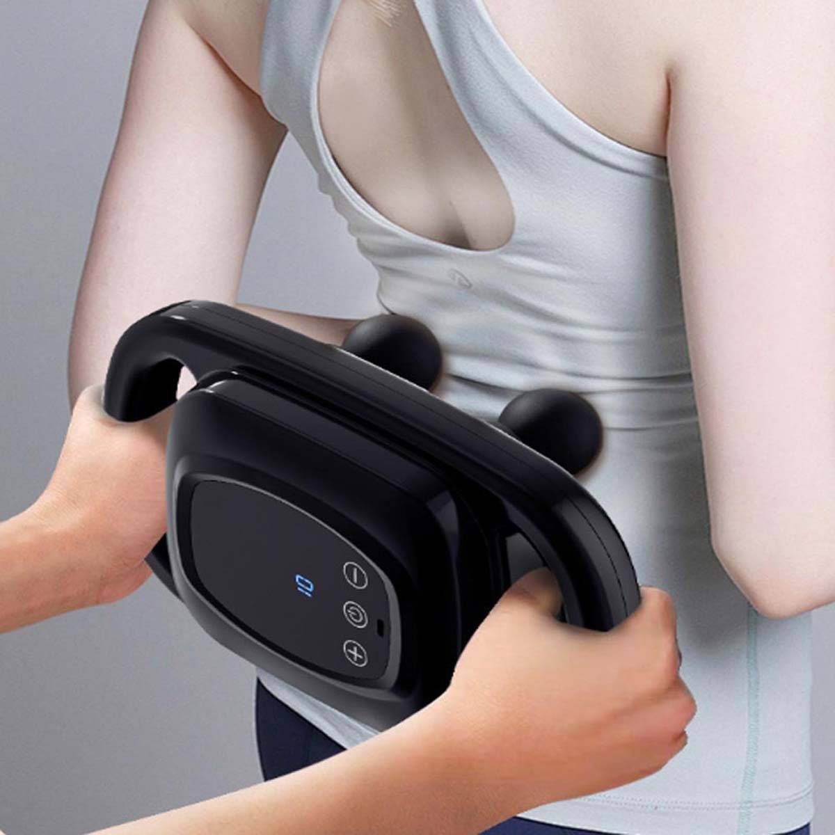 Frau, die ein schwarzes tragbares Massagegerät auf ihrem Bauch verwendet, drückt es gegen ihren Oberkörper für Körpermassage oder Muskelentlastung.