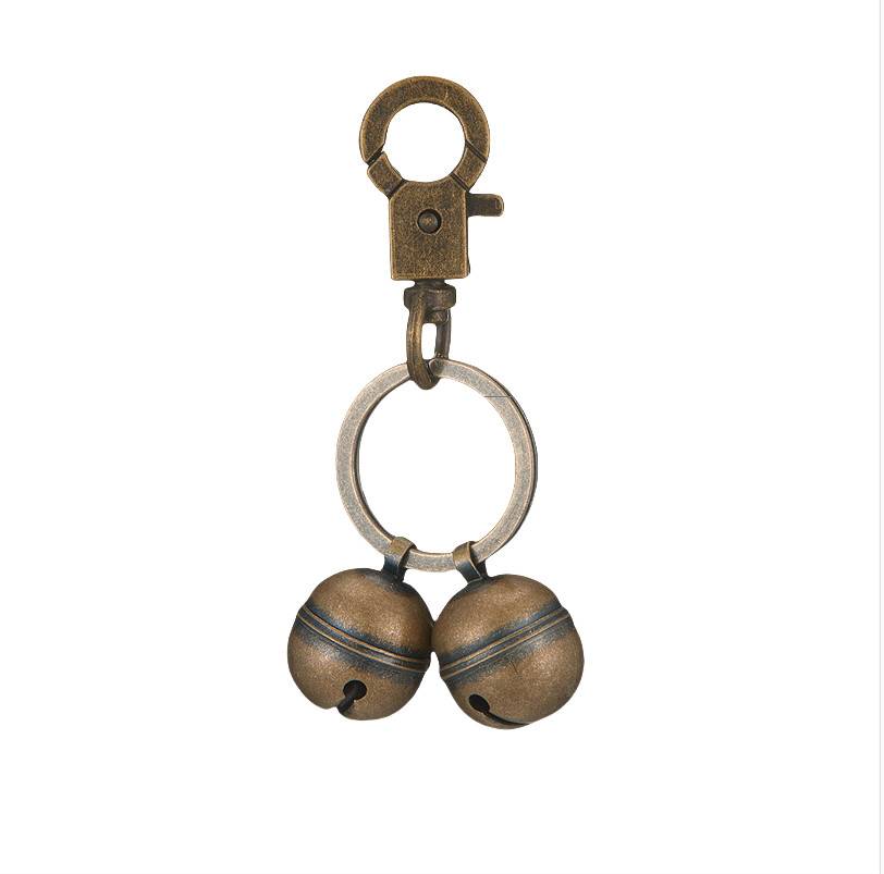 Metallschlüsselanhänger mit Drehverschluss und Ring, an dem zwei bronzefarbene Schellen befestigt sind.