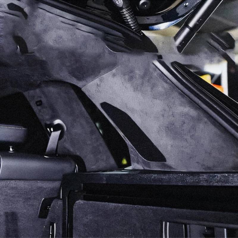 Nahaufnahme des Laderaums eines Autos mit dunkelgrauer Polsterung, Rückenlehne und Verkleidungspanelen.