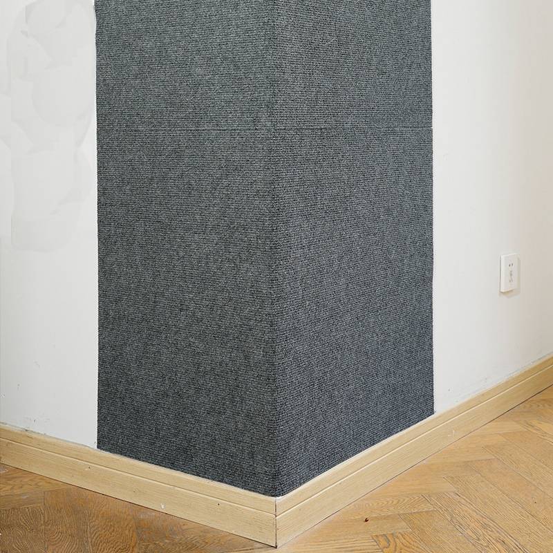Ecke eines Zimmers mit einer dunkelgrauen strukturierten Akzentwandverkleidung über einer hellen Holzleiste und einem Fischgrätmuster-Boden neben einer weißen Wandsteckdose.