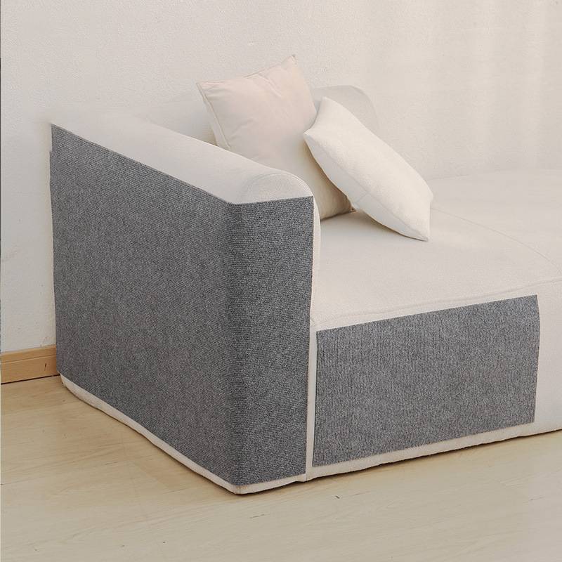 Modernes grau-weißes Schlafsofa mit zwei cremefarbenen Kissen in einem minimalistischen Raum.