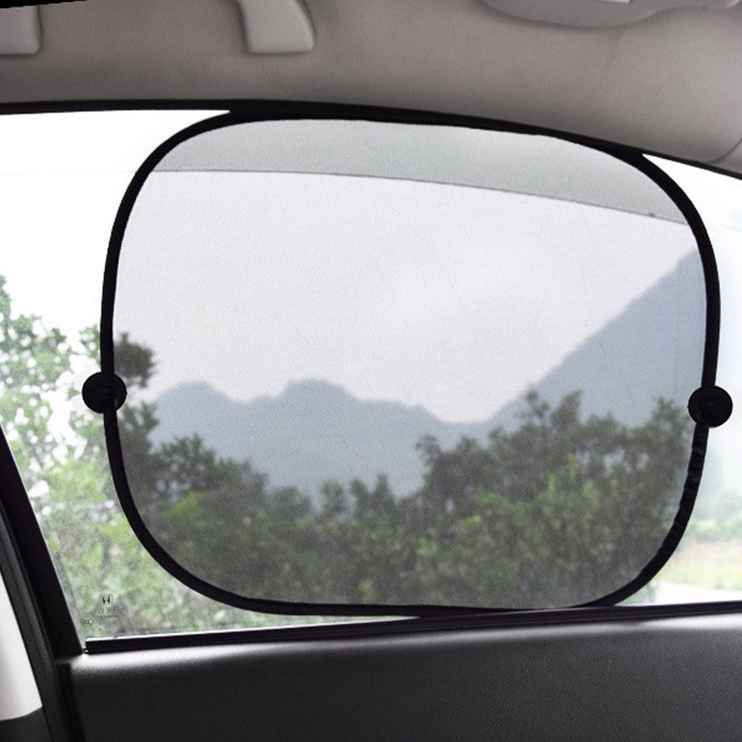 Autofenster-Sonnenschutz, der an der Scheibe befestigt ist, filtert helles Licht und verdeckt teilweise die Aussicht auf Bäume und entfernte Berge draußen.