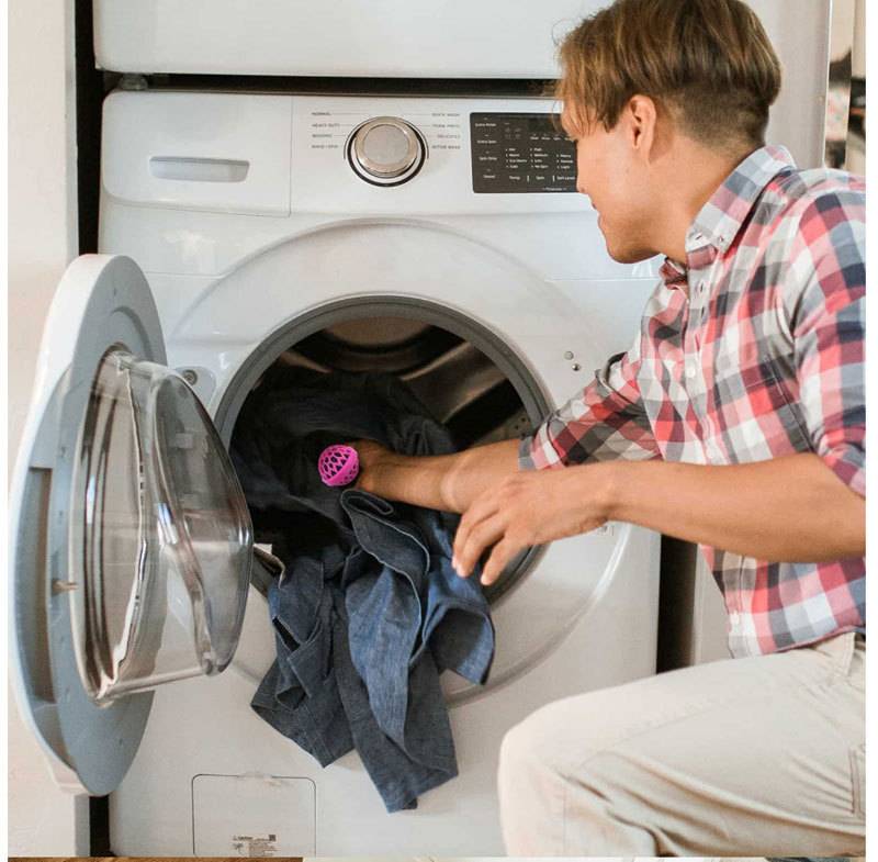 Ein Mann lädt Kleidung in eine Frontlader-Waschmaschine zu Hause.