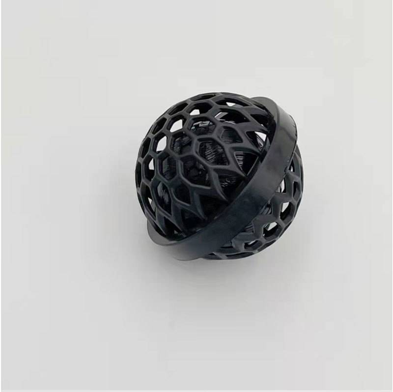 Schwarzes kugelförmiges Gittersspielzeug mit einem breiten Ring, der darum gewickelt ist, gezeigt auf einem schlichten weißen Hintergrund.