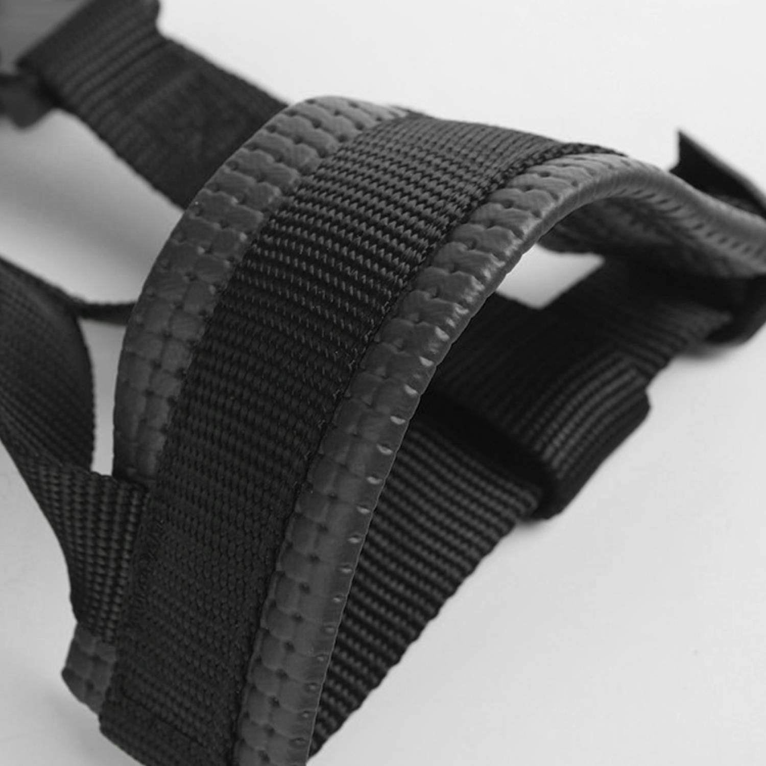 Nahaufnahme eines schwarzen Nylon-Webbandes mit gepolstertem Griff und gesäumten Kanten, wahrscheinlich Teil einer Tasche oder eines Geschirrs.