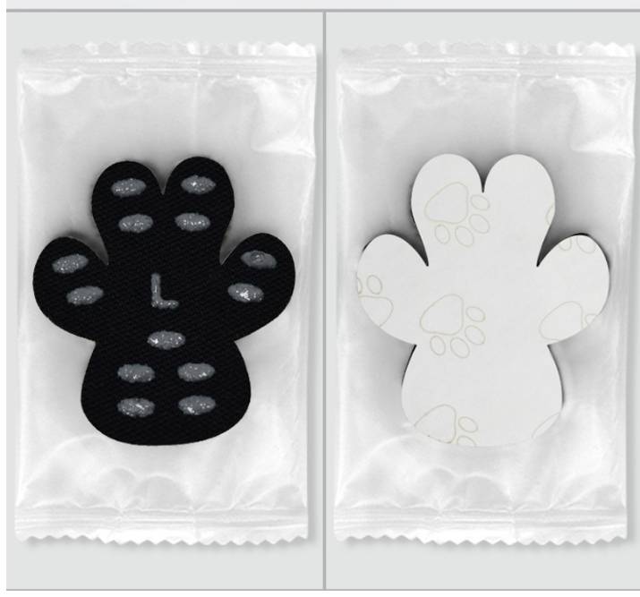 Zwei verpackte pfotienförmige Haftpads, eines schwarz und eines weiß, jeweils mit strukturierten Griffpunkten.