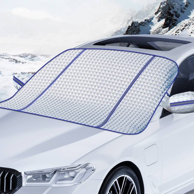 Weißes Auto mit einer gesteppten Windschutzscheibenschutzdecke, geparkt in einer verschneiten Berglandschaft zum Schutz der Scheibe vor Frost und Schnee.