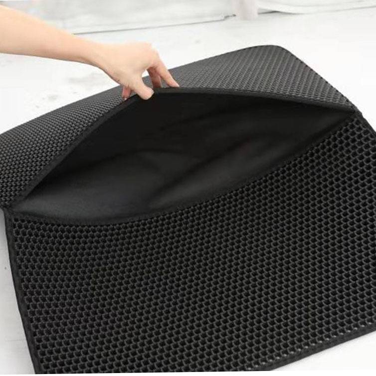 Hand hebt eine schwarze, wabenstrukturierte Gummimatte an, um ihre flexible Unterseite und dunkle Rückseite zu zeigen