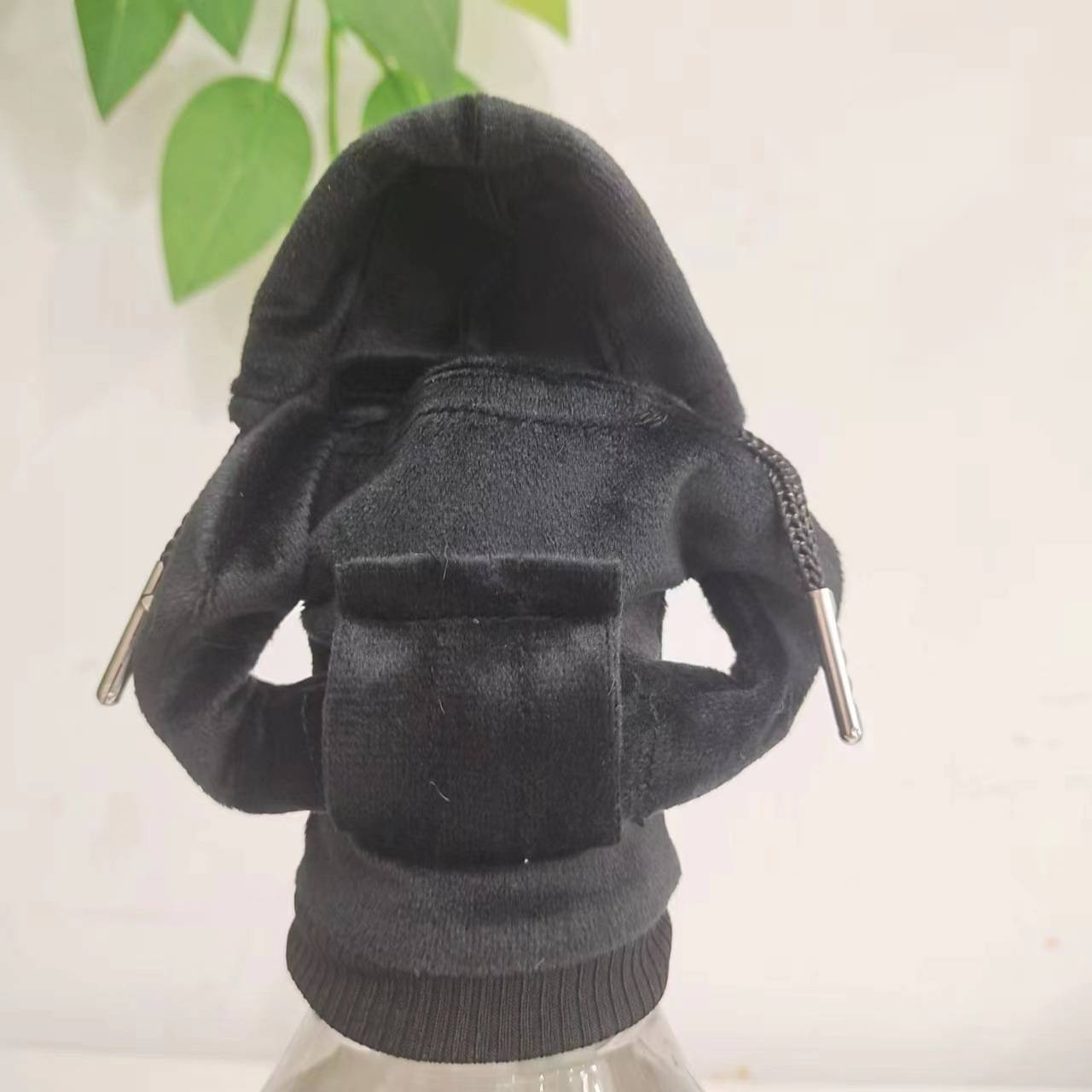 Schwarzer Kapuzenpullover von hinten gezeigt, mit Zugschnüren und geripptem Saum, zentriert vor einem einfachen hellen Hintergrund.