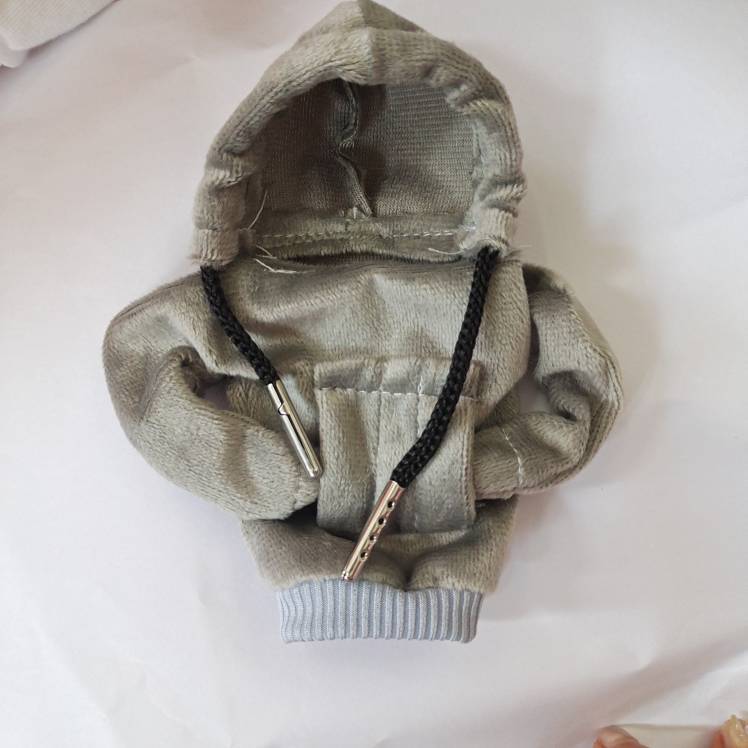 Kleiner grauer Kapuzen-Sweatshirt für ein Haustier mit schwarzen Kordelzügen und geripptem Saum, flach auf weißem Hintergrund ausgelegt.