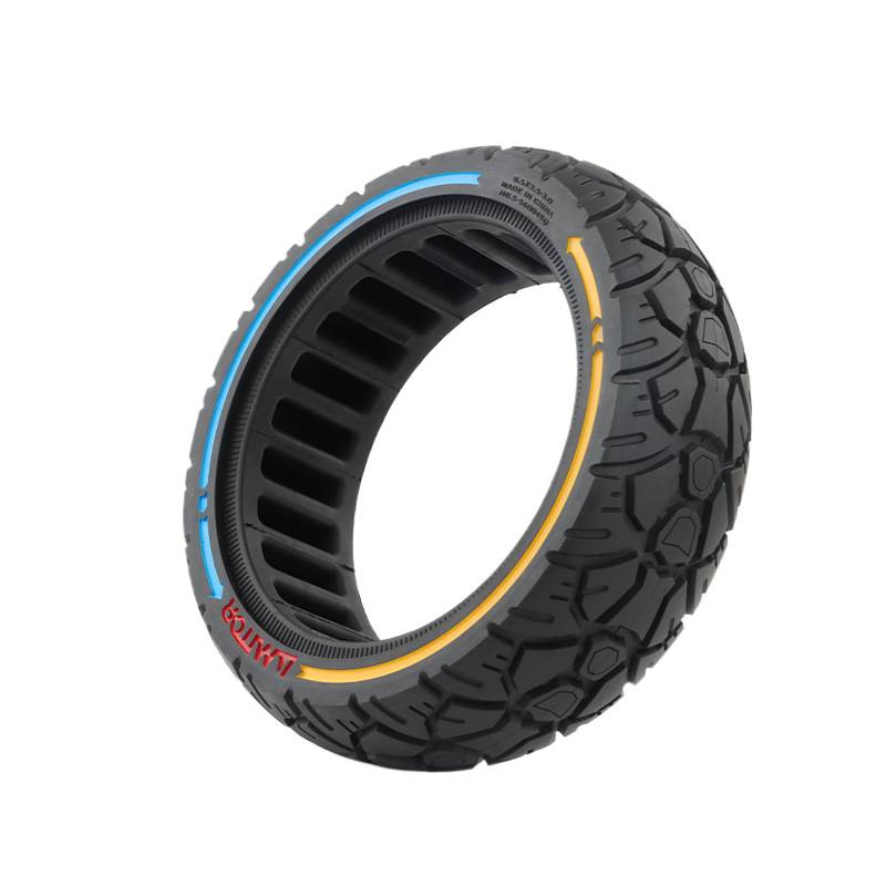 Schwarzer Offroad-Roller-Reifen mit tiefem Profil und blauen, gelben und roten Akzentstreifen auf weißem Hintergrund.