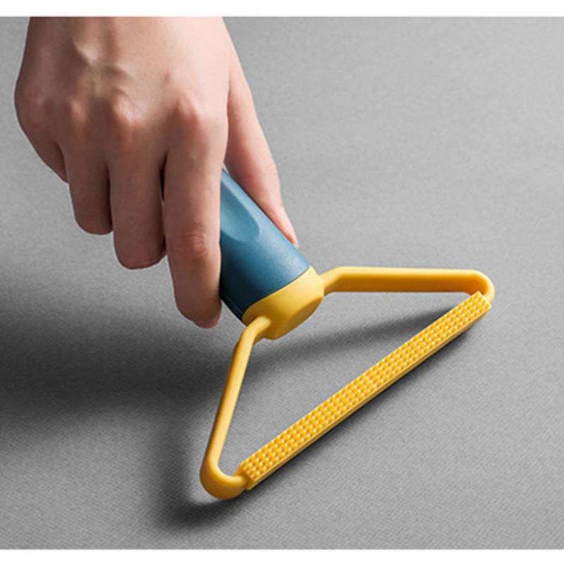Hand, die eine Fusselrolle verwendet, um Flusen von einer grauen Stoffoberfläche zu entfernen.
