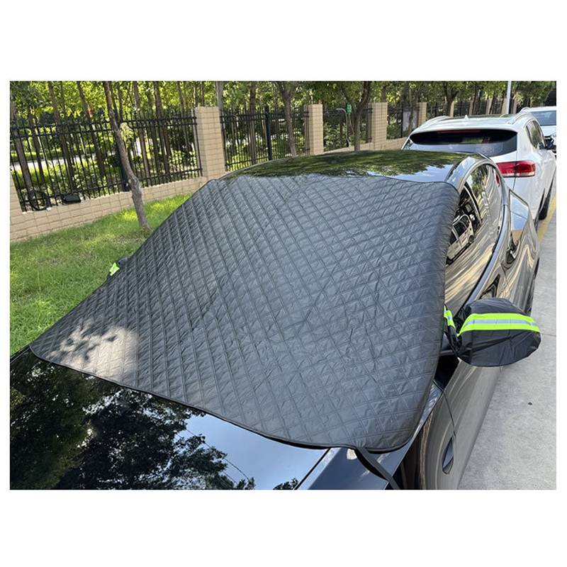 Schwarzierter gesteppter Windschutzscheiben-Sonnenschutz bedeckt die Frontscheibe eines geparkten Autos auf einer Straße, mit einem weiteren Auto dahinter.