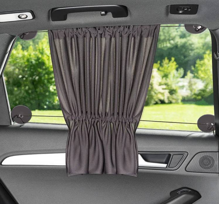 Heckfenster eines Autos mit einem zentrierten grauen Sichtschutzvorhang, der die Aussicht nach außen durch das Fenster der Rückbank blockiert.