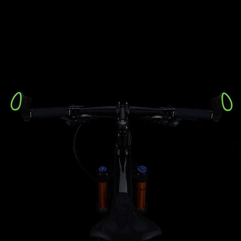 Vorderansicht eines Mountainbike-Lenkers und einer Gabel auf schwarzem Hintergrund, mit neongrünen Lenkerringenden und sichtbaren blauen Gabelkappen.