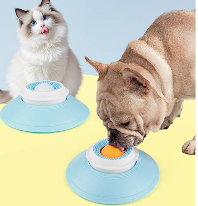 Zwei Haustiere nutzen interaktive Futterspielzeuge: ein Hund leckt einen Ball auf einer blauen Basis und eine Katze sitzt hinter einem anderen identischen Spielzeug.