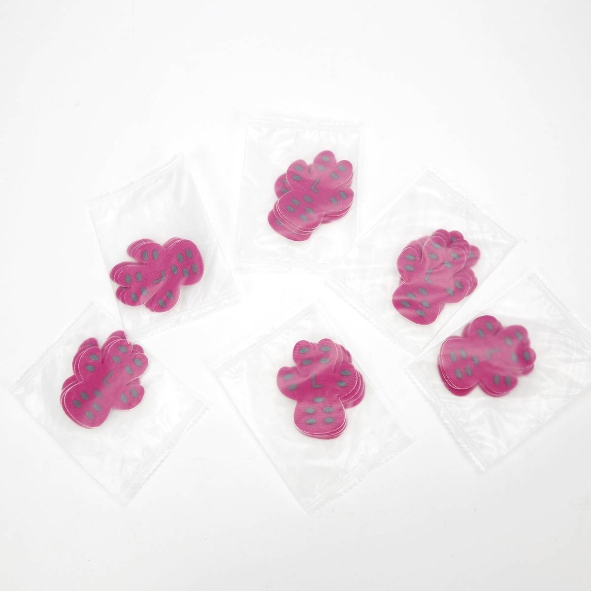 Sechs kleine durchsichtige Plastiktüten, jede mit einem rosa blumenförmigen Stück auf weißem Hintergrund.