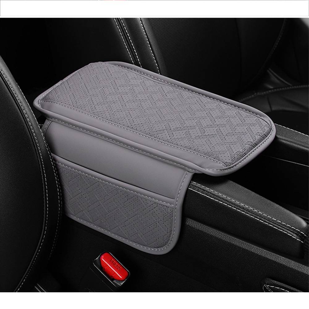 Grauer gepolsterter Armlehnenüberzug auf einer Automobil-Mittelkonsole zwischen schwarzen Vordersitzen installiert, der Polsterung und Schutz bietet.