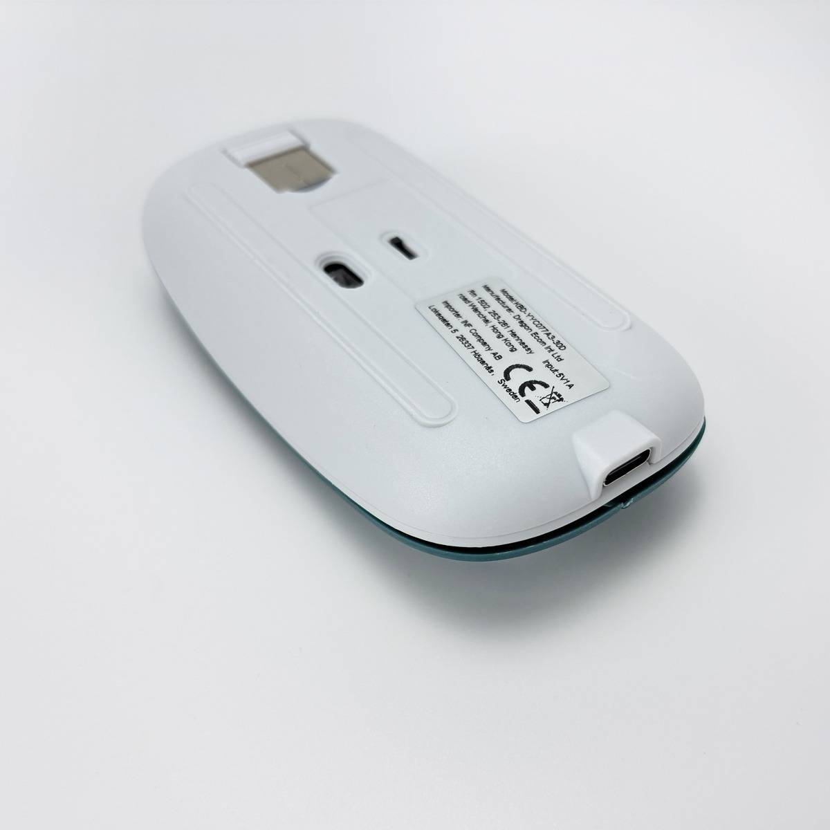 Weiße kabellose Computermaus, auf den Kopf gestellt dargestellt, mit sichtbarem Sensor und Batteriefachetikett auf einfachem weißem Hintergrund.
