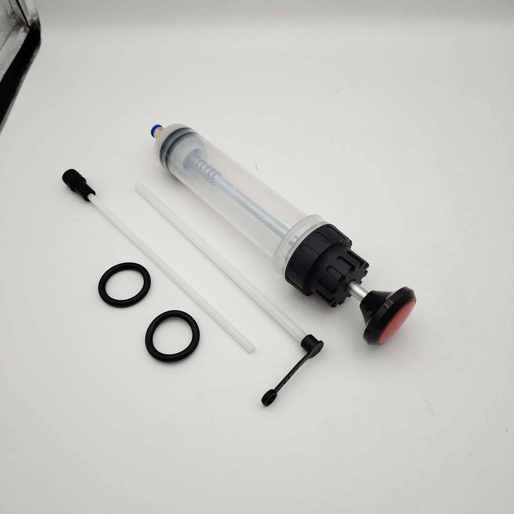 Auseinandergelegter transparenter Kunststoffspender in Spritzen-Form mit schwarzer Kappe, Kolben, zwei O-Ringen und kleinen Rohrteilen auf einer weißen Oberfläche.