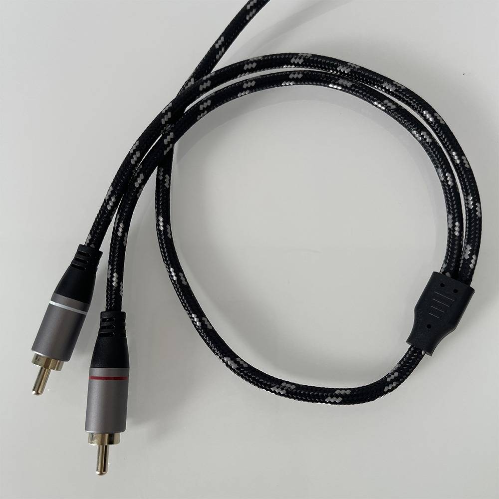 Geflochtenes schwarzes Audiokabel mit zwei RCA-Steckern auf einfarbigem Hintergrund.