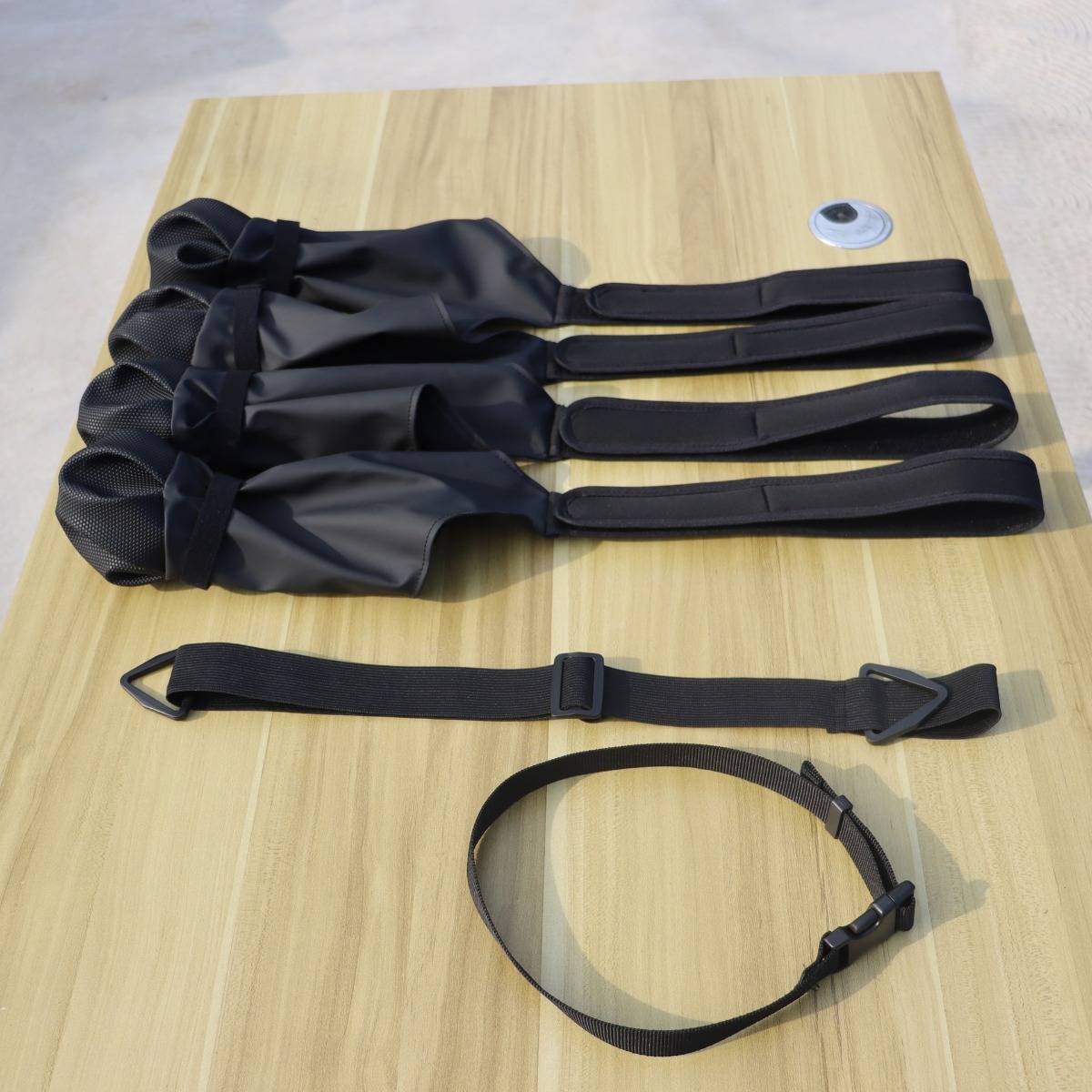 Schwarze Nylonriemen und ein Schleifengurt auf einem Holztisch ausgelegt, vermutlich Befestigungs- oder Sicherungsriemen.