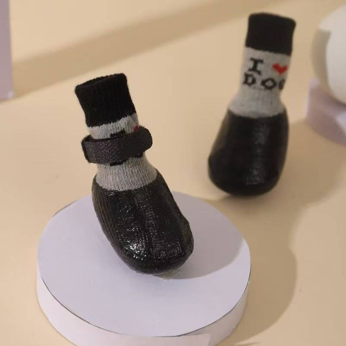 Zwei kleine schwarze sockenähnliche Figürchen mit weißen Manschetten sind auf einem weißen runden Podest ausgestellt, eine vorne und eine hinten, mit "I ♥ D"" auf der hinteren Figur sichtbar.