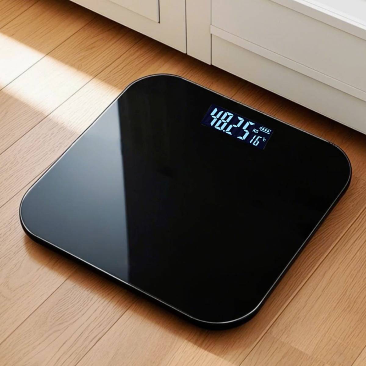 Digitale schwarze Personenwaage auf einem Holzboden, die 48,2 und 16°C auf ihrem Display anzeigt.