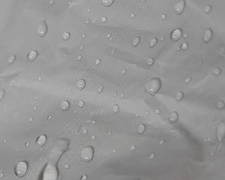 Nahaufnahme von grauem wasserdichtem Stoff mit verstreuten Wassertropfen auf der Oberfläche.
