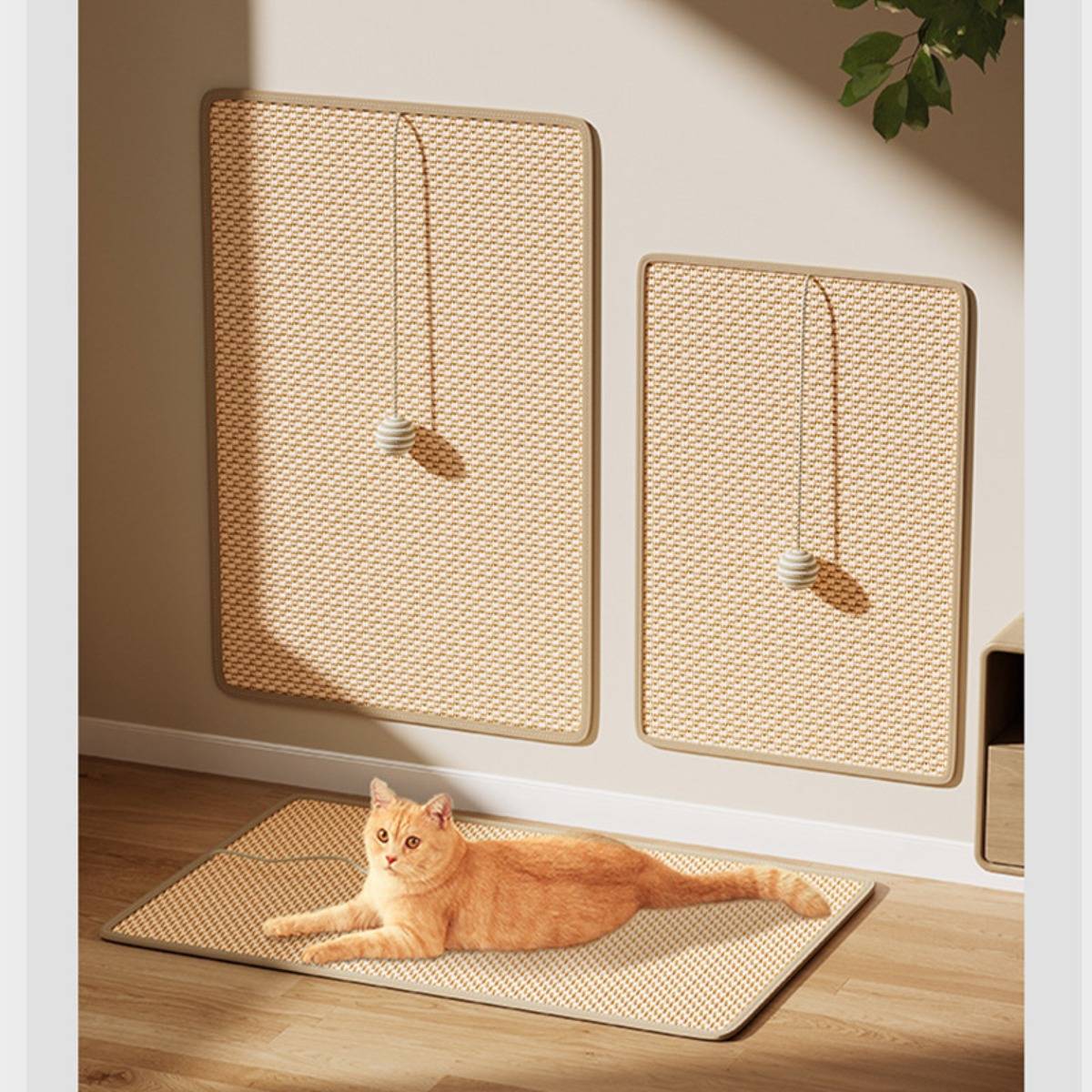Zwei geflochtene Kratzpaneele für Katzen an einer Wand und eine passende Bodenmatte, auf der eine orange Katze in einem sonnigen Zimmer liegt.