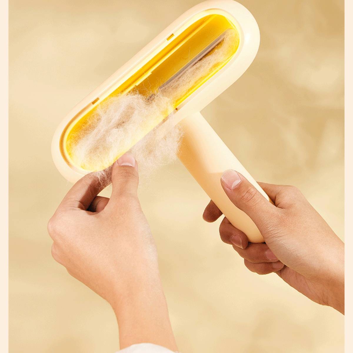 Hände verwenden eine gelbe Fusselrolle, um Flusen von einem Stoff vor einem beigen Hintergrund zu entfernen.