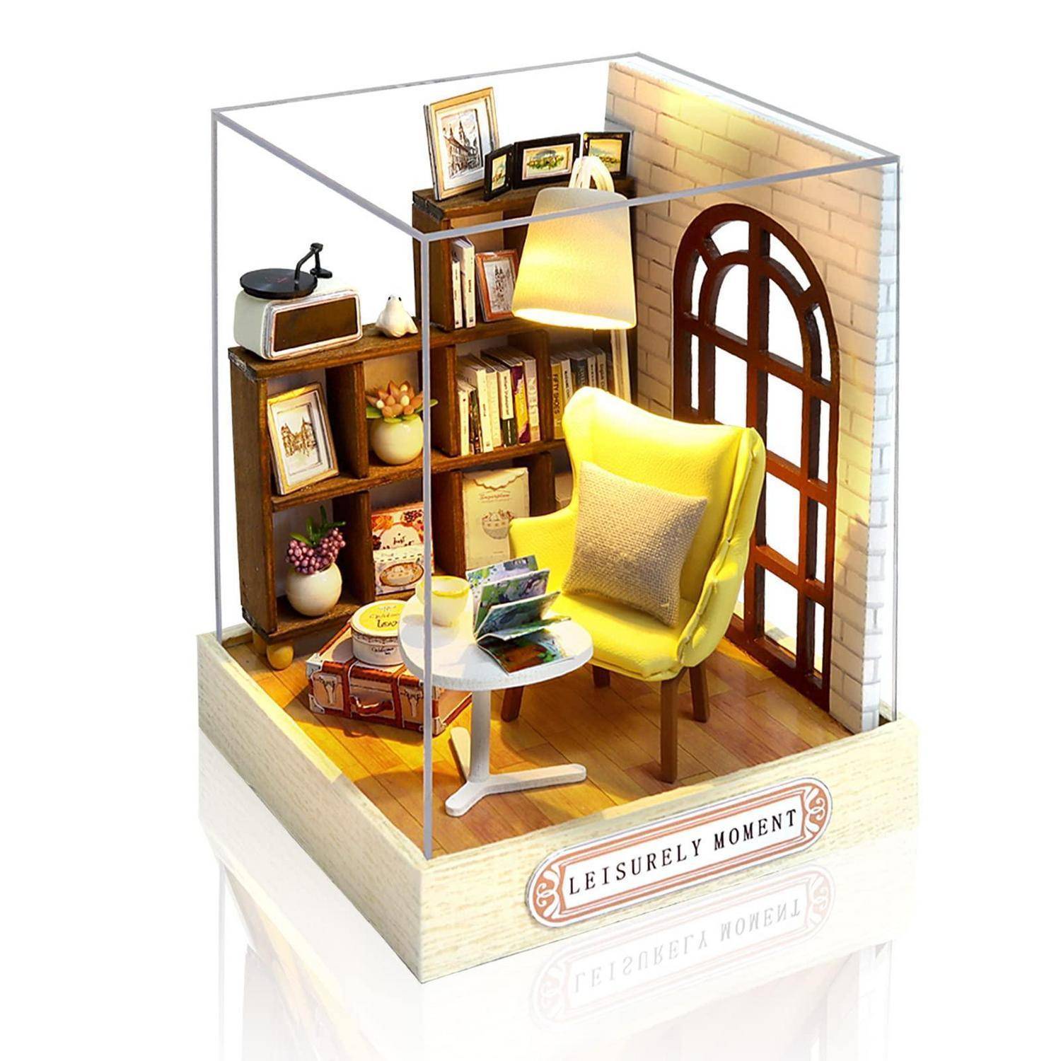 Miniatur-Gemütliche Raumdiorama mit gelbem Sessel, Bücherregal, Lampe, kleinem Tisch und Rundbogenfenster mit der Aufschrift „LEISURELY MOMENT