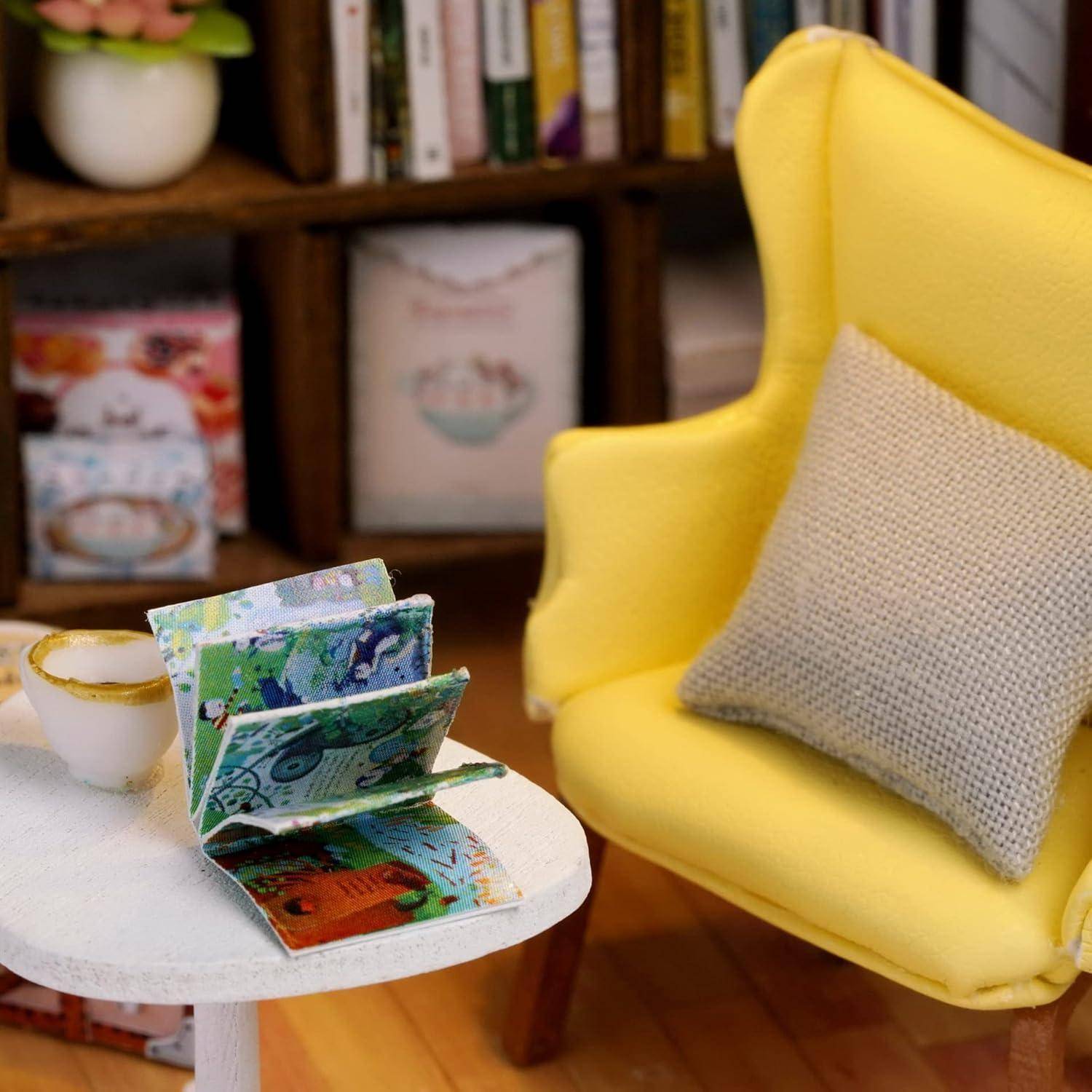 Leuchtend gelber Sessel mit einem beigen Kissen neben einem kleinen weißen Tisch, auf dem ein offenes, farbiges gefaltetes Buch oder eine Karte sowie eine Tasse in einem gemütlichen Zimmer zu sehen sind.